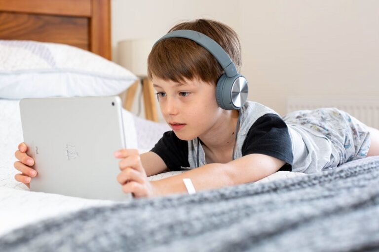 Niño en la cama escuchando música (Emily Wade Unsplash)
